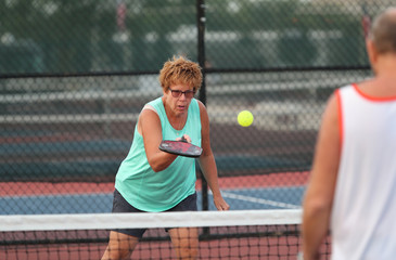 A senior woman plays pickleball