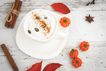Spicy pumpkin latte coffe, autumn hot drink white cup, with pumpkins, cinnamon and spices on old rustic wooden background copy space