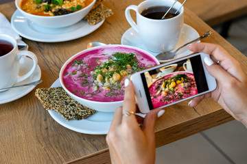 Food eating, technology, culinary and people concept - woman hands with smartphone photographing soup at restaurant