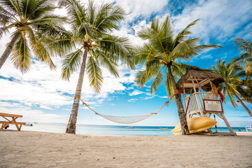 Naklejka premium hammock between palms trees. cloudy sky, ocean