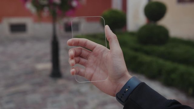 Close-up view of young person's hand using mobile transparent phone with futuristic augmented relality glass. Visual effects. For animation.
