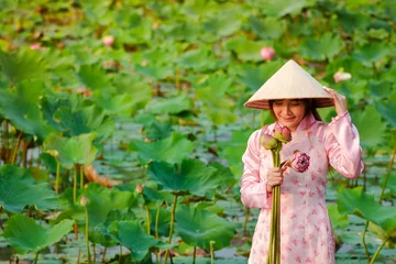 Foto op Canvas Vietnamese girl wearing a pink dress holding a lotus flower © SUPERMAO