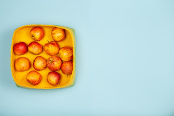 Apples in yellow baskets over a light blue background with large copy space.