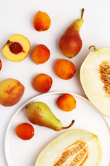 Sliced ripe juicy melon, apricots and pears on a white background. Top view.