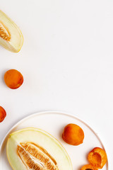 Sliced ripe juicy melon, apricots and pears on a white background. Top view.
