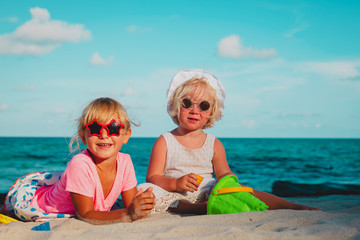 cute girls play with sand on summer beach