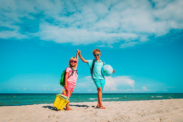 kids travel on beach, boy and girls with backpack, globe and toys at sea