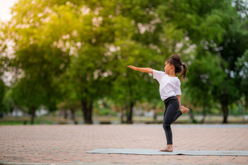 Little cute asian girl practicing yoga pose on a mat in park, Healthy and exercise concept