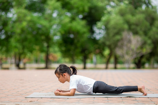 Little cute asian girl practicing yoga pose on a mat in park, Healthy and exercise concept