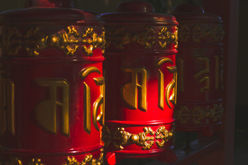 close up red buddhist temple drums with carved with golden letters mantras