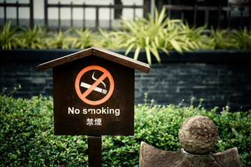 No smoking label put on wooden plate and garden background
