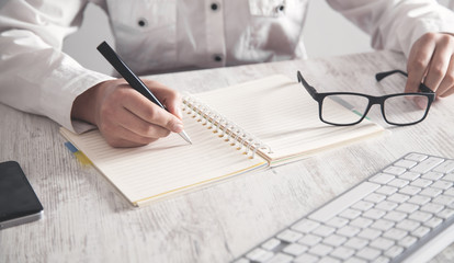 Girl writing on notepad in office desk.