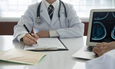 medical concept. doctor take notes on medical report with stethoscope on cardiogram chart on desk at doctor office.