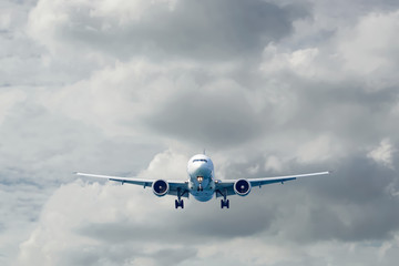 Passenger plane in flight. Aircraft fly high in the sky above the clouds. Front view of airplane.