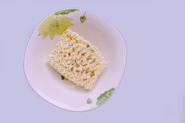 On the plane of the table is a plate with a dry briquette of pasta for quick preparation of meals,...