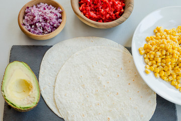 Ingredients for Mexican vegetarian tacos in bowls on light table, close-up