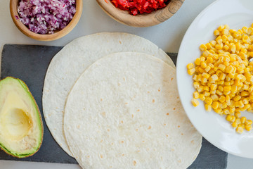 Ingredients for Mexican vegetarian tacos in bowls on light table, close-up