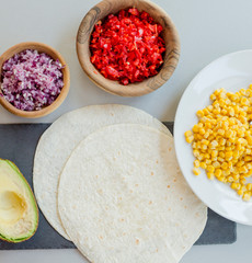 Ingredients for Mexican vegetarian tacos in bowls on light table, close-up