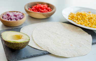 Ingredients for Mexican vegetarian tacos in bowls on light table, close-up