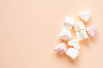 Heart shaped marshmallows on a beige background. Marshmallows in the shape of pink and white hearts.