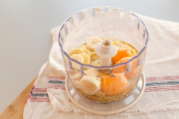 Blender bowl with eggs and banana slices with cereals, eating healthy concept