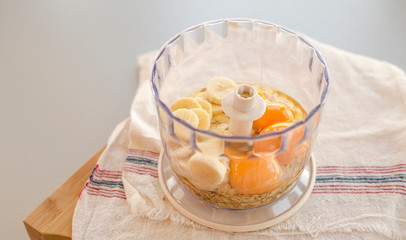 Blender bowl with eggs and banana slices with cereals, eating healthy concept