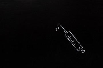 Medical concept - syringe for injection painted with white chalk on the board