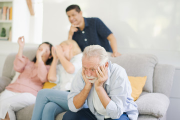 Group of positive seniors European and Asia are sitting on the big sofa and talking which looking television at retirement home. Retired old people are felling sad.