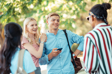 Cheerful couple talking with their university friends.