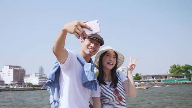 Couples use smartphones selfie on boat in Chao Phraya River, Bangkok Thailand.