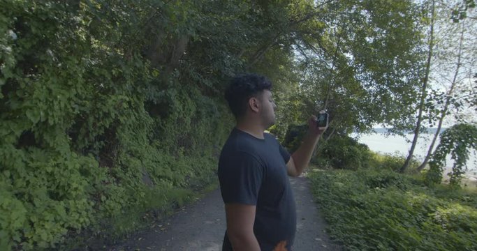 Slow Motion Hispanic Male Takes Photo in the Trees and Lowers Phone as Camera Pulls Away