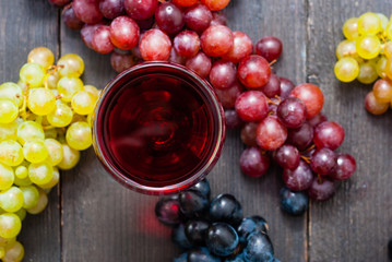 glass of red wine and grapes on black wooden table background