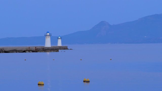 Breakwater and seamark on the blue sea at dusk. Scenic seascape on foggy day. A ship's allotted place at a wharf or dock. Seamark for boats, ships, liners. Coastal zone. Twilight on the wharf, dock