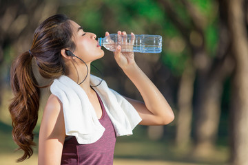 Asian young woman drinking water after jogging 