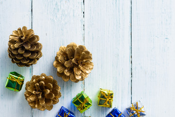 gold painted pine cone and gift box on white wood