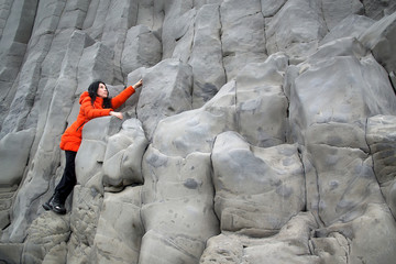 Female traveler walking on rocky formations at Reynisfjara Beach, Vik, Iceland
