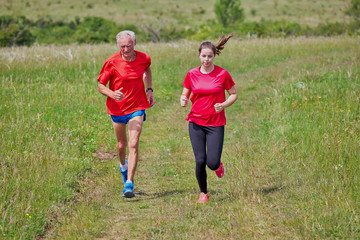 Fototapeta premium Senior man and his grandchild running on the meadow