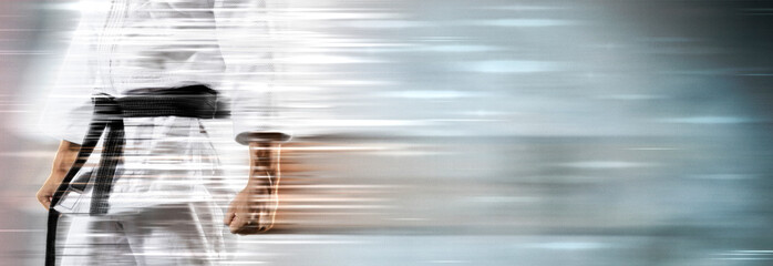 Guy poses in white kimono with black belt on motion background
