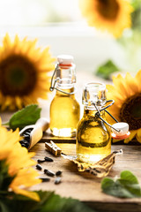 Sunflower oil in a bottle glass with seeds and flowers of sunflower. on blurred background