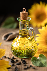 Sunflower oil in a bottle glass with seeds and flowers of sunflower. on blurred background