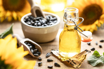 Sunflower oil in a bottle glass with seeds and flowers of sunflower. on blurred background