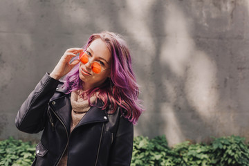 Woman in orange sunglasses and with colorful dyed hair.