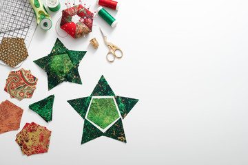 Preparation of pentagon and triangular pieces of fabric for sewing patchwork star, quilting accessories. Space for text.