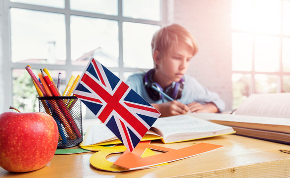 Focused schoolboy studying english reading textbook in classroom