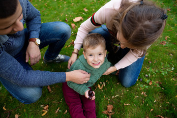 Family of three enjoy autumn park having fun smile