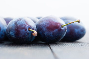 plums on black wood table, front view
