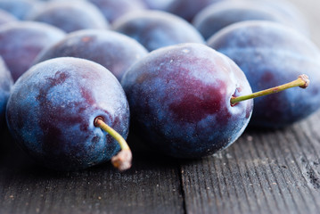 plums on black wood table, front view
