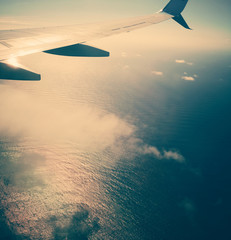 Naklejka na ściany i meble vacation - airplane flying above the clouds