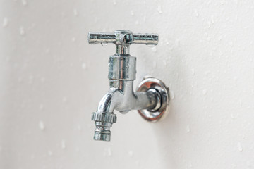 silver metal faucet in the wall on a white background water source adjustment of pressure water...