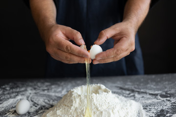 the process of making dough for pasta, the chef broke a raw chicken egg over a pile of flour